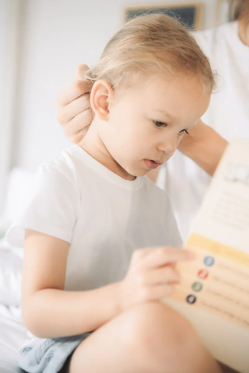 Criança lendo um livro no colo de um adulto